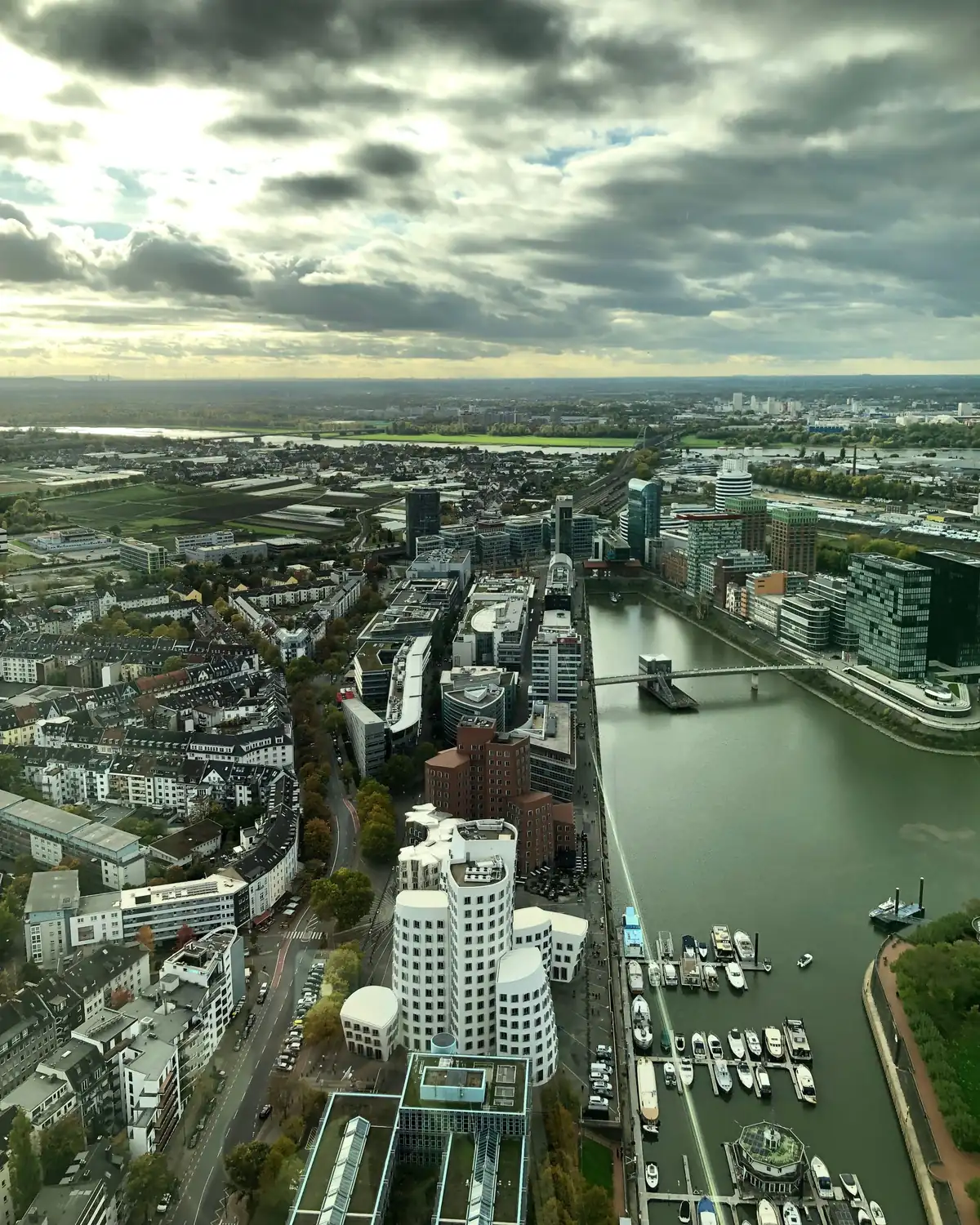 Blick vom Rheinturm auf den Düsseldorfer Medienhafen mit den Gehry-Bauten, daneben die Wohnstraßen von Unterbilk und dahinter der Rhein